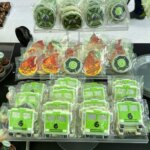 Assorted themed cookies on display, including green fire trucks with the number 6, fire department badges, and flame shapes, all individually wrapped in clear plastic.