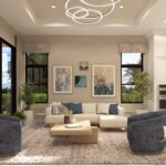 Modern living room with beige sofa, two blue swivel chairs, abstract wall art, large windows, indoor plants, and a contemporary chandelier, adjacent to a white marble kitchen.